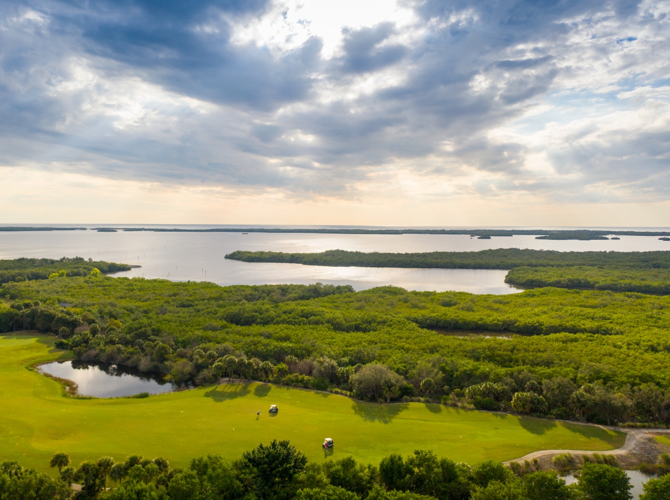 An aerial view of the Saltleaf Golf Preserve, a championship golf course in Bonita Springs, with a scenic lake.