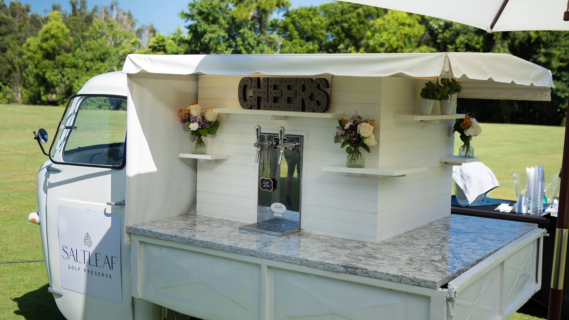 A vw bus transformed into a unique mobile bar, perfect for serving refreshing beverages atop the scenic Saltleaf Golf Preserve in Bonita Springs.