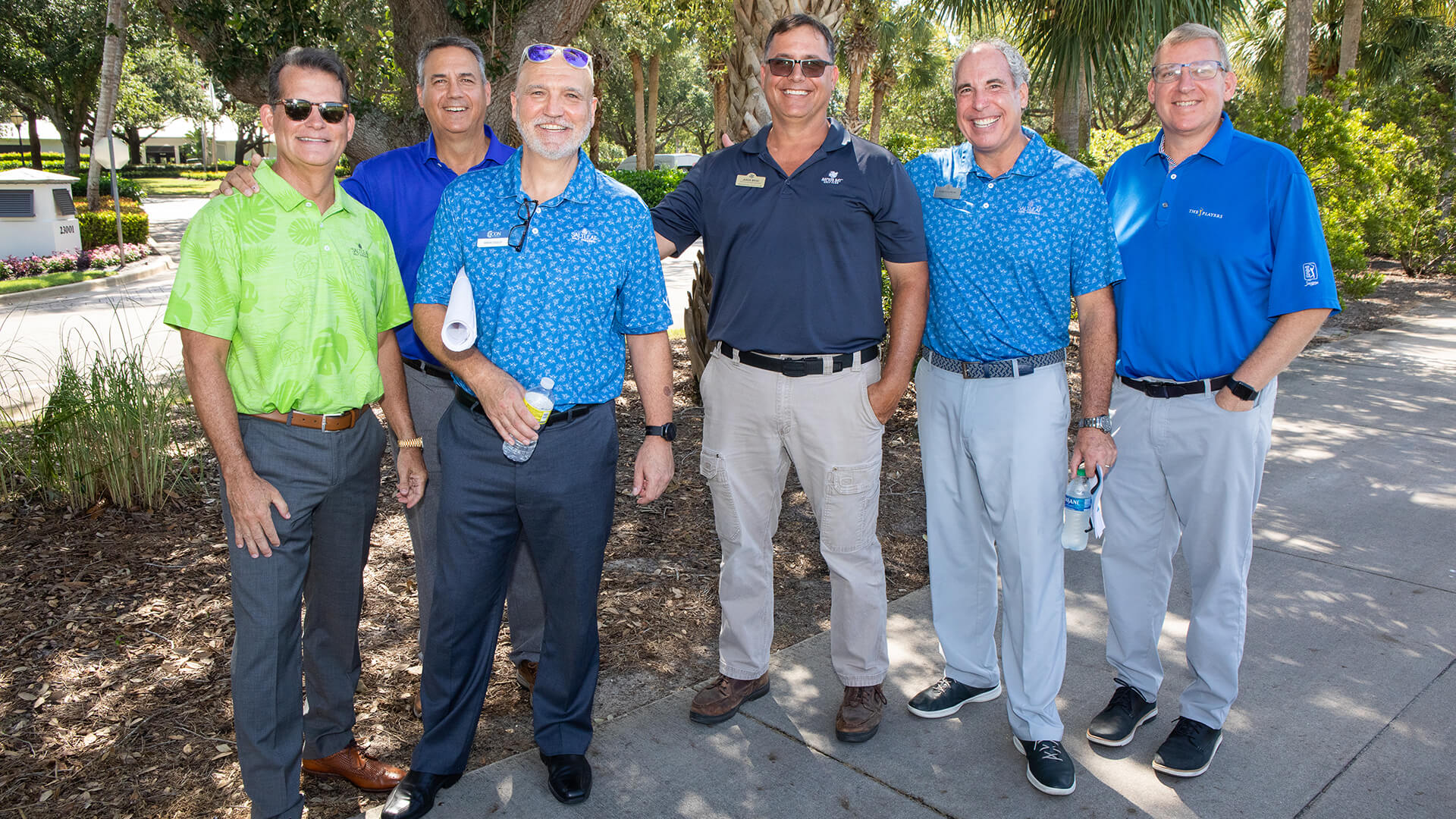 A group of men in blue shirts posing for a photo at the championship golf course in Bonita Springs.