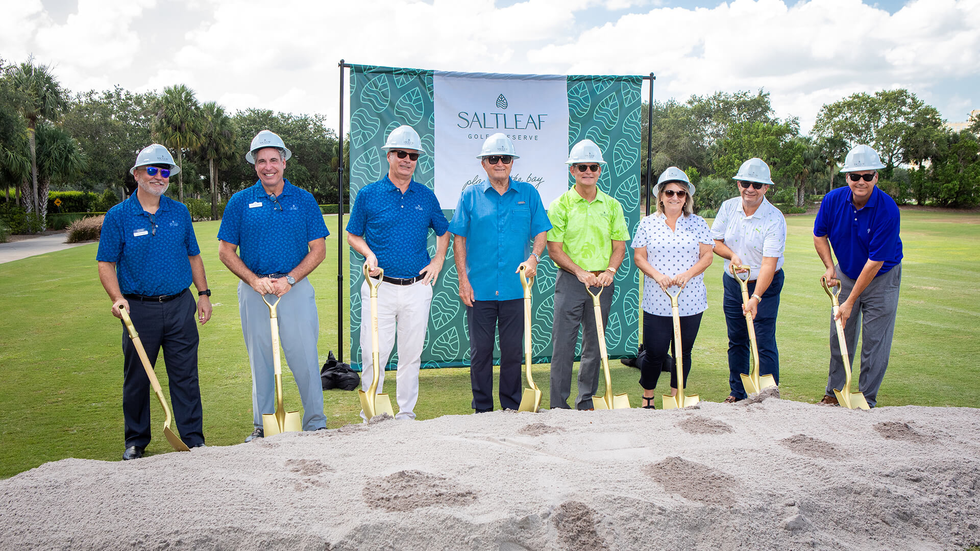 A group of people standing in front of a pile of sand at Saltleaf Golf Preserve, a championship golf course in Bonita Springs.