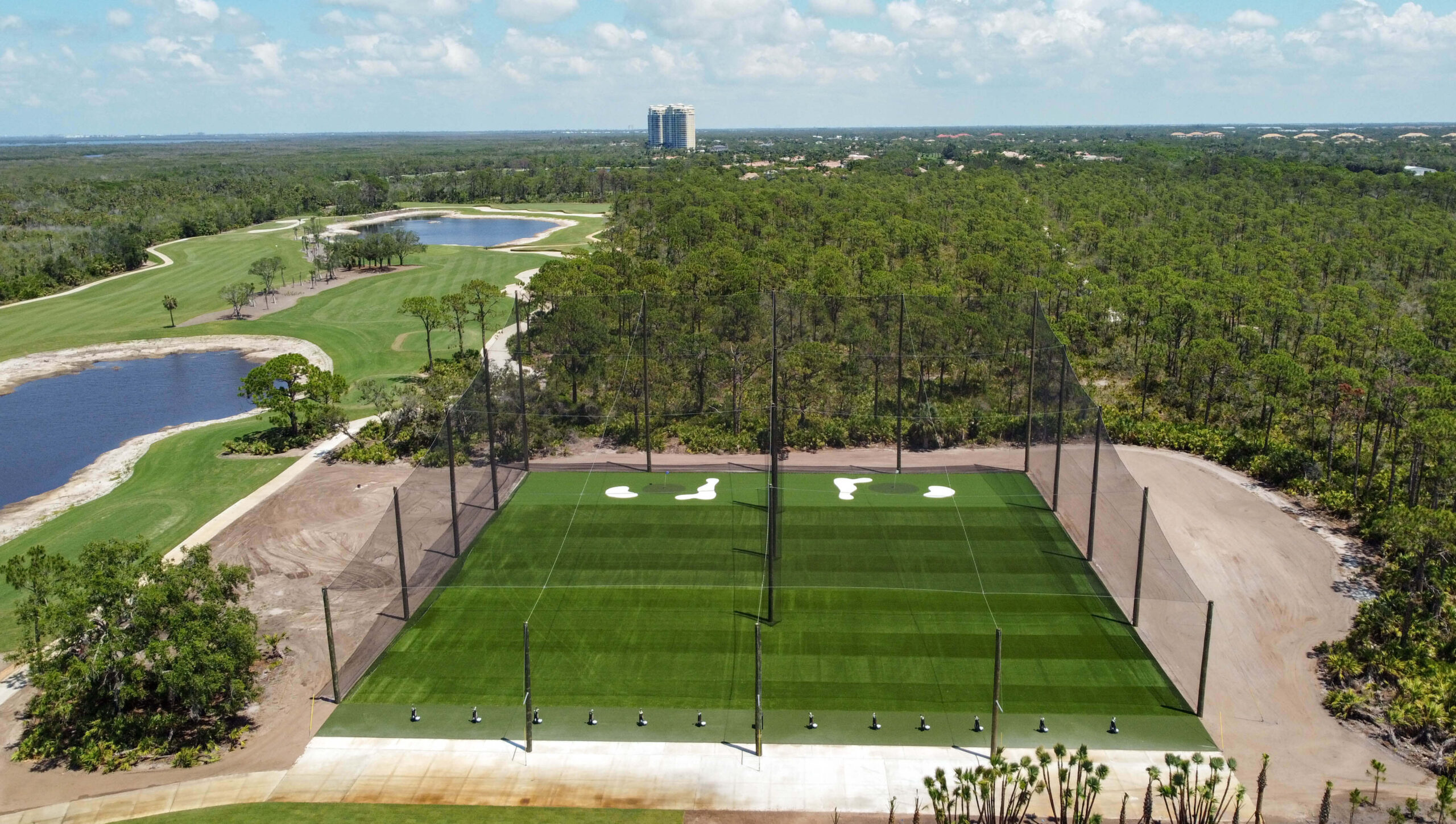 Aerial image of the netted driving range at Saltleaf Golf Preserve with nature and water in the background