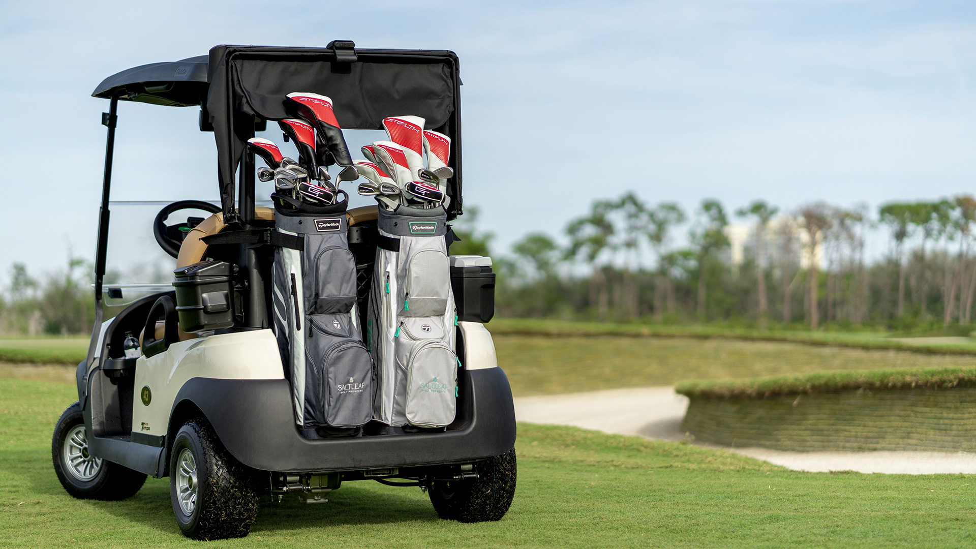 A golf cart equipped with golf clubs roams the championship golf course of Saltleaf Golf Preserve in Bonita Springs.