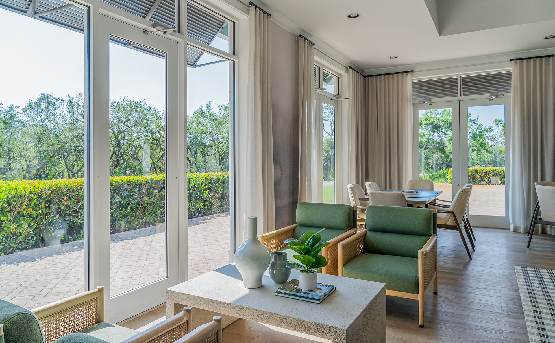 A living room in the beautiful Saltleaf Golf Preserve community, with sliding glass doors offering stunning views of the neighboring championship golf course in Bonita Springs.
