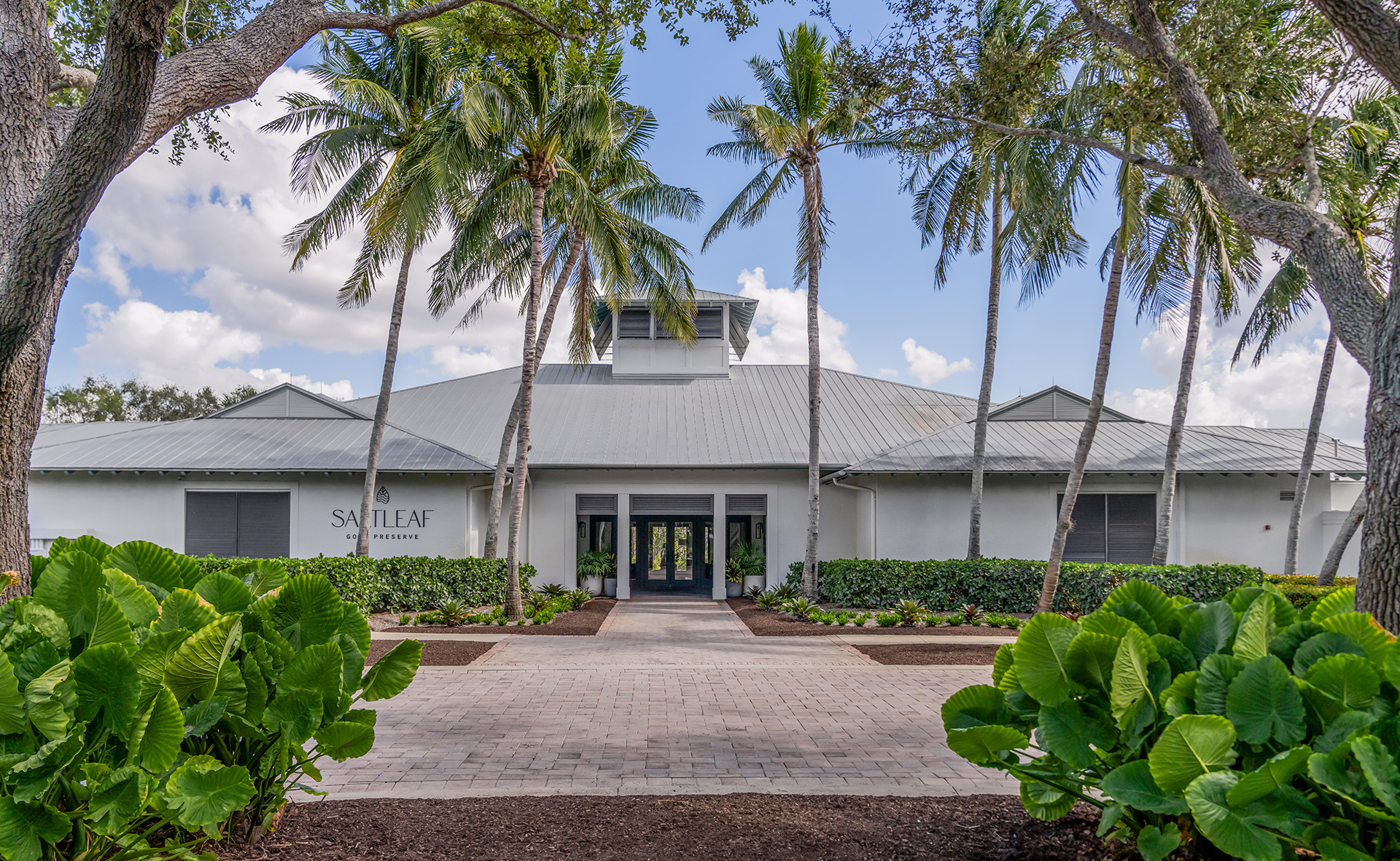 The entrance to the Saltleaf Golf Preserve, a white building with palm trees, located in Bonita Springs.